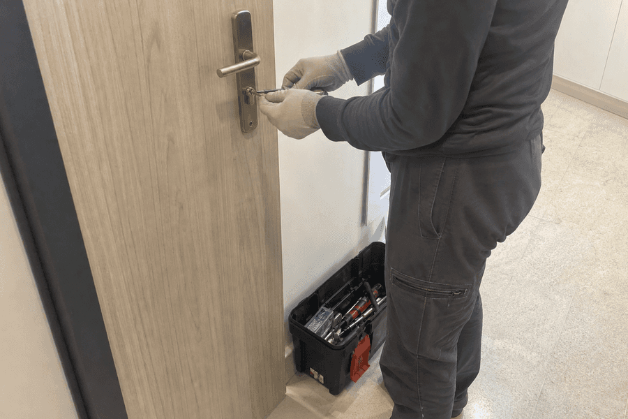 Main effectuant ouverture de porte avec outil spécialisé