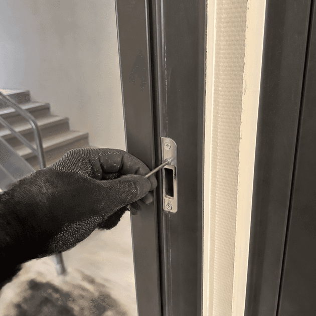 Mains réglant la gâche d'une porte d'appartement